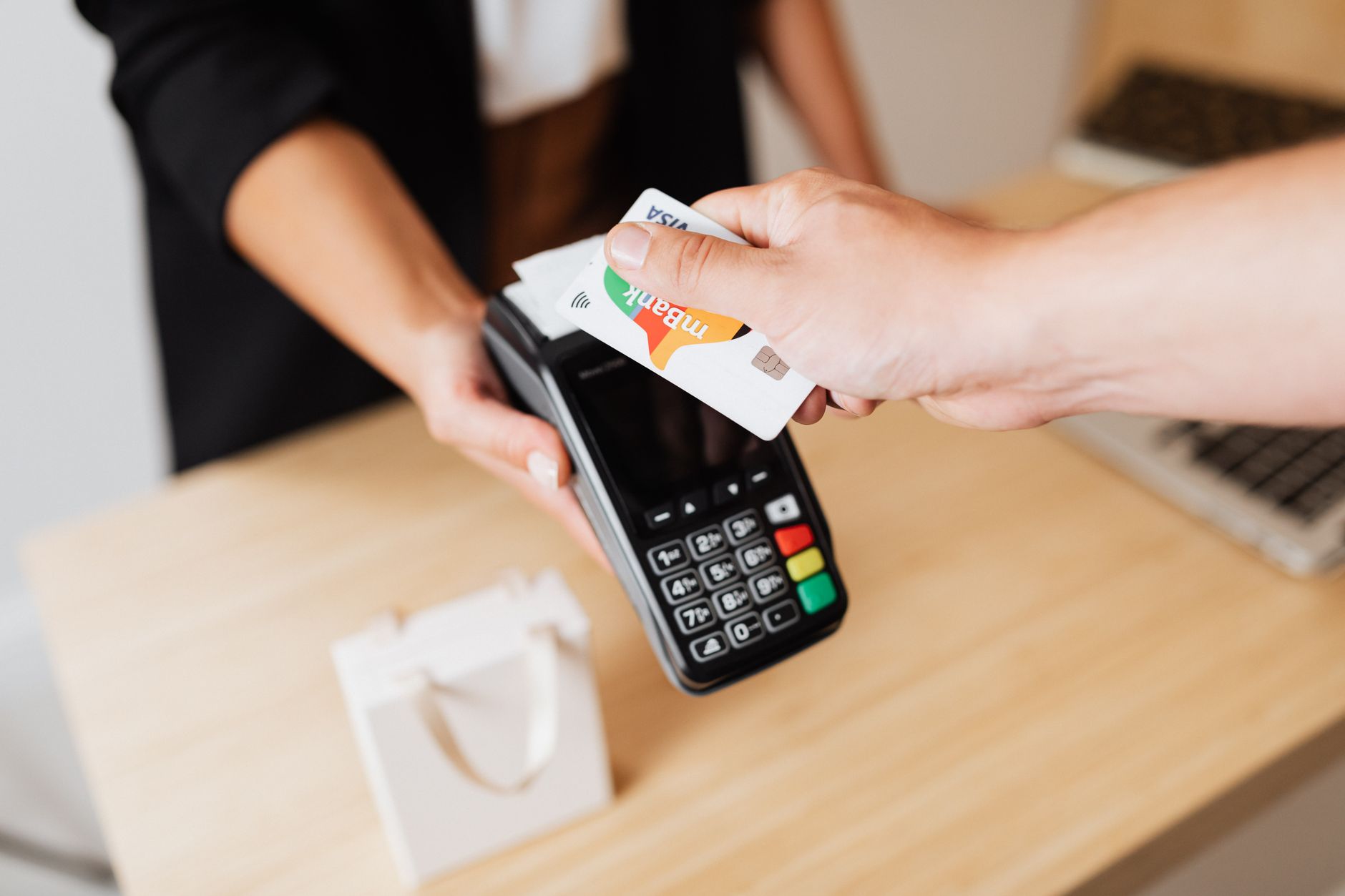 Cliente aproximando o cartão de uma maquininha no balcão de uma loja